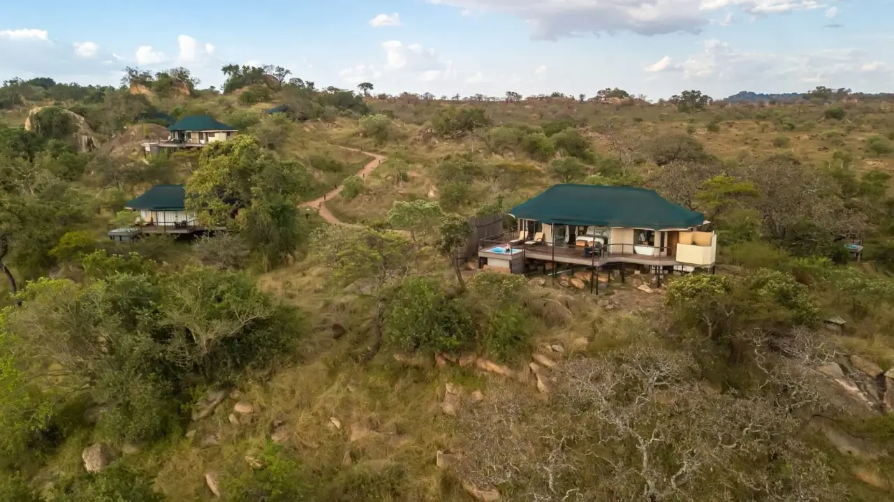 Aerial view of tented suites with private plunge pools scattered across a rocky kopje at Lemala Kuria Hills
